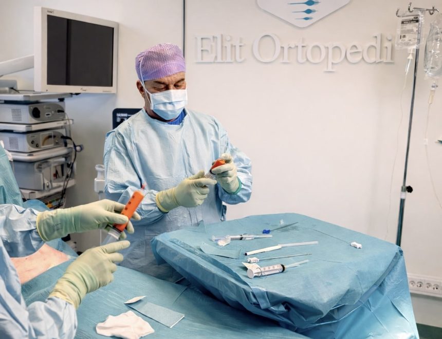 Orthopedic specialist in blue surgical scrubs harvesting and preparing stem cells for regenerative joint treatment in a modern operating room at Elit Ortopedi, Stockholm.