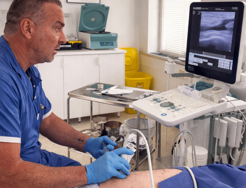 Ortopedspecialist utför ultraljudsledd PRP-behandling av knä i klinikmiljö